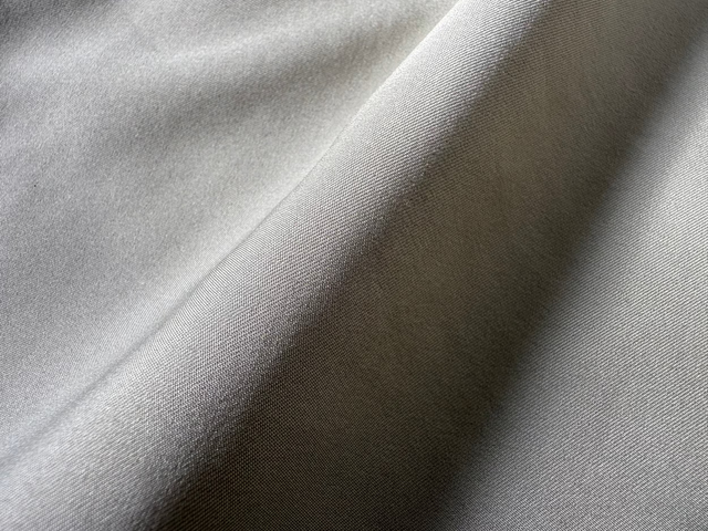 Close-up of Vault Urban shirt fabric in taupe green, showing smooth texture and sustainable high-performance weave