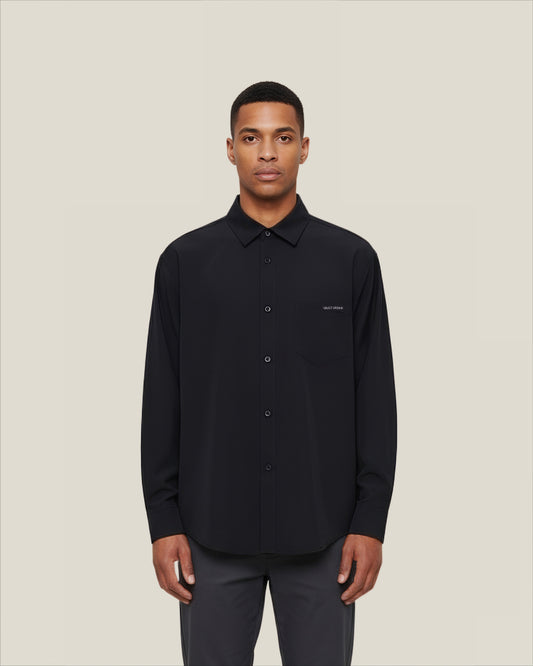 Man wearing a black shirt with a small logo on a beige background